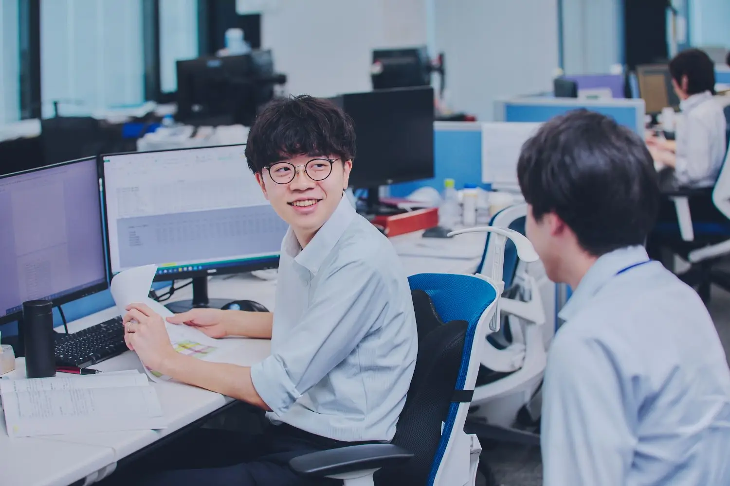デスクで仲間と作業をしている男性